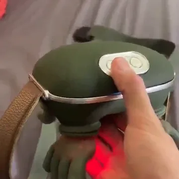 Das Massagegerät in der Hand, ein Finger auf der Taste, die Wärmeflächen leuchten rot